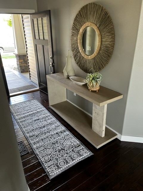 Indoor foyer entryway with front door, console table, round mirror and runner rug